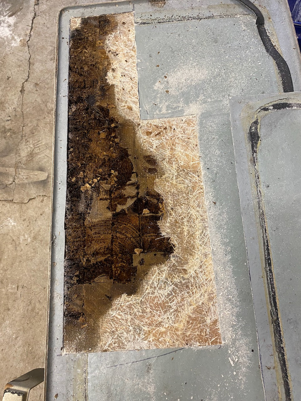 Impact-damaged fiberglass deck section with the gelcoat ground away