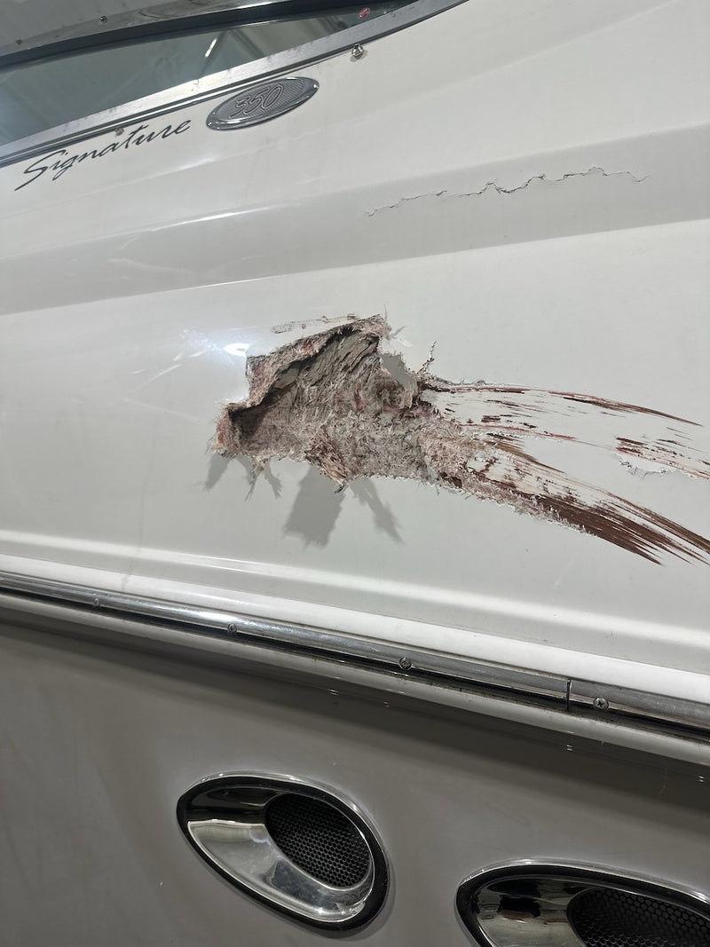 Impact damage on a boat's hull side with the fiberglass torn open