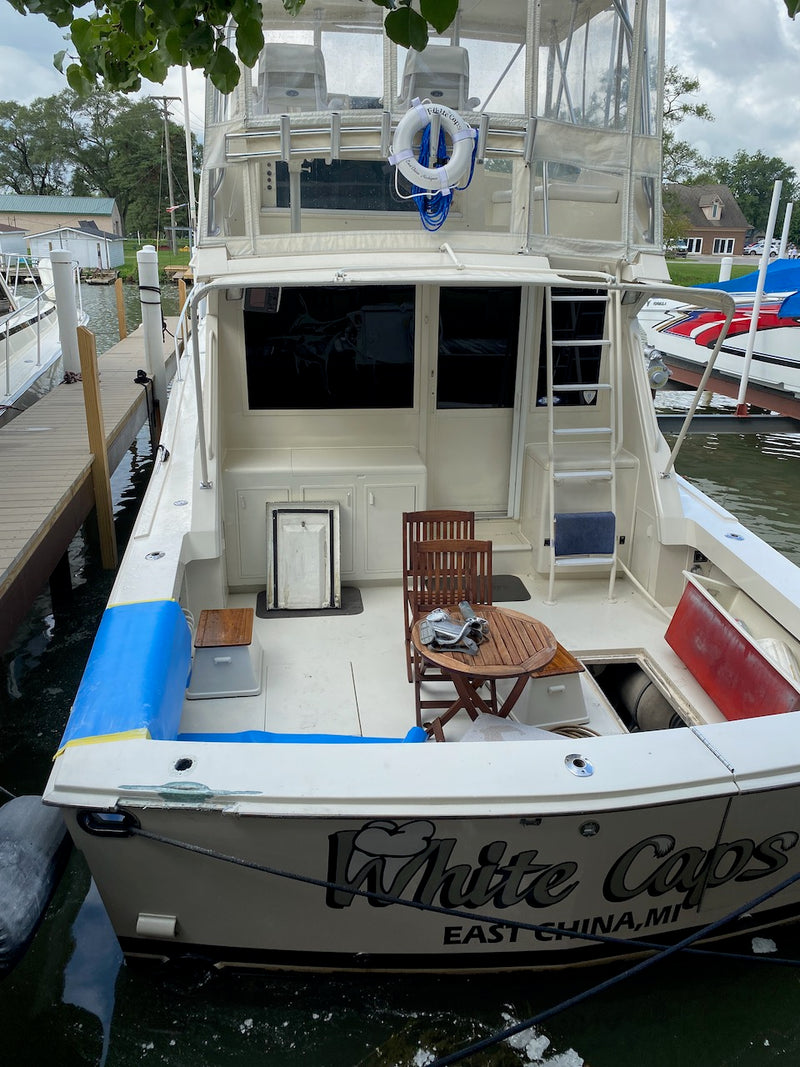 Sportfish boat at the dock seen from the stern, with blue masking tape on the hull