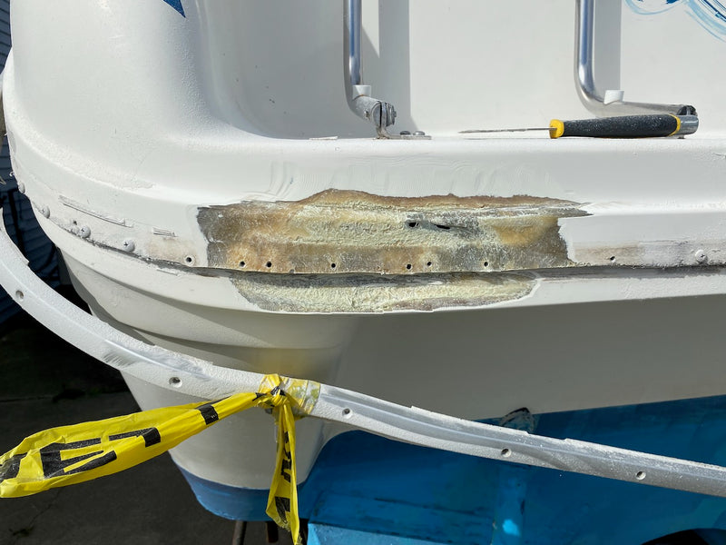 Boat stern corner with a gouged, ground-out fiberglass repair under caution tape